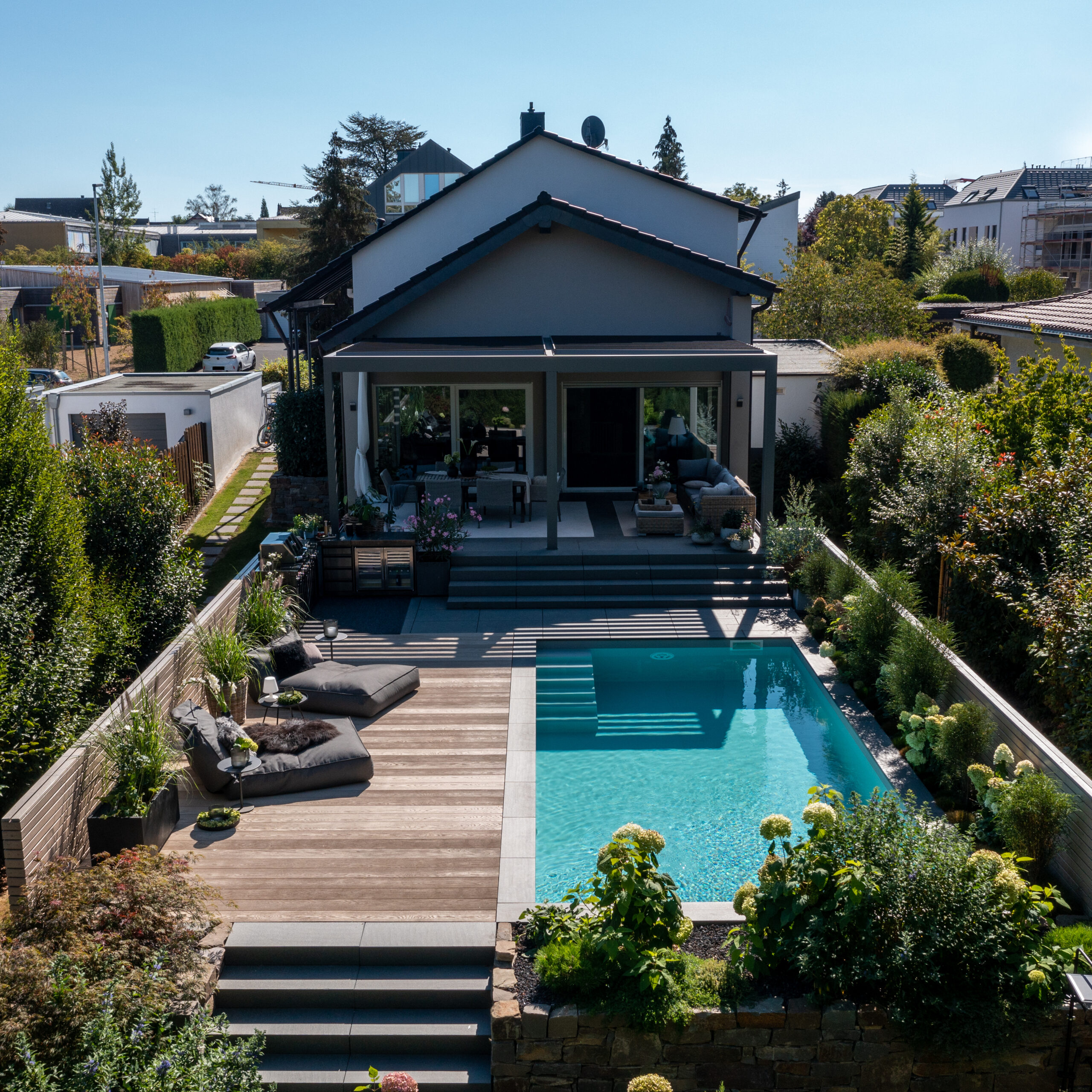 Pool vor überdachter Sitzecke mit Liegen und Haus