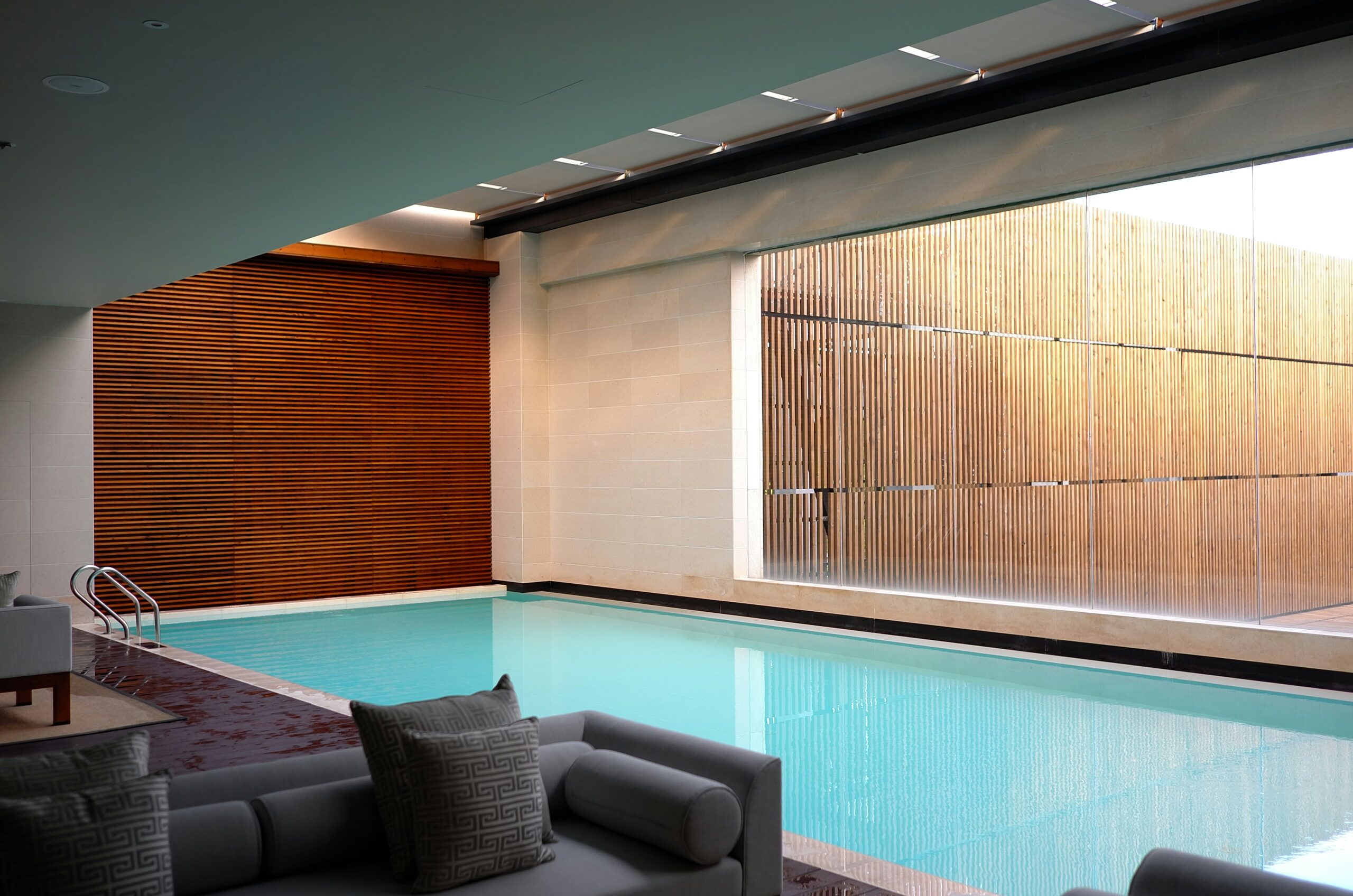 Indoor Pool mit Glasscheibe und Holzwand